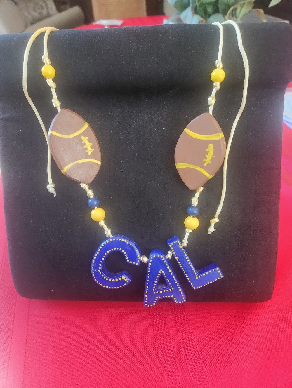 Handmade wooden football necklace with blue 'CAL' letters and yellow dots #cal